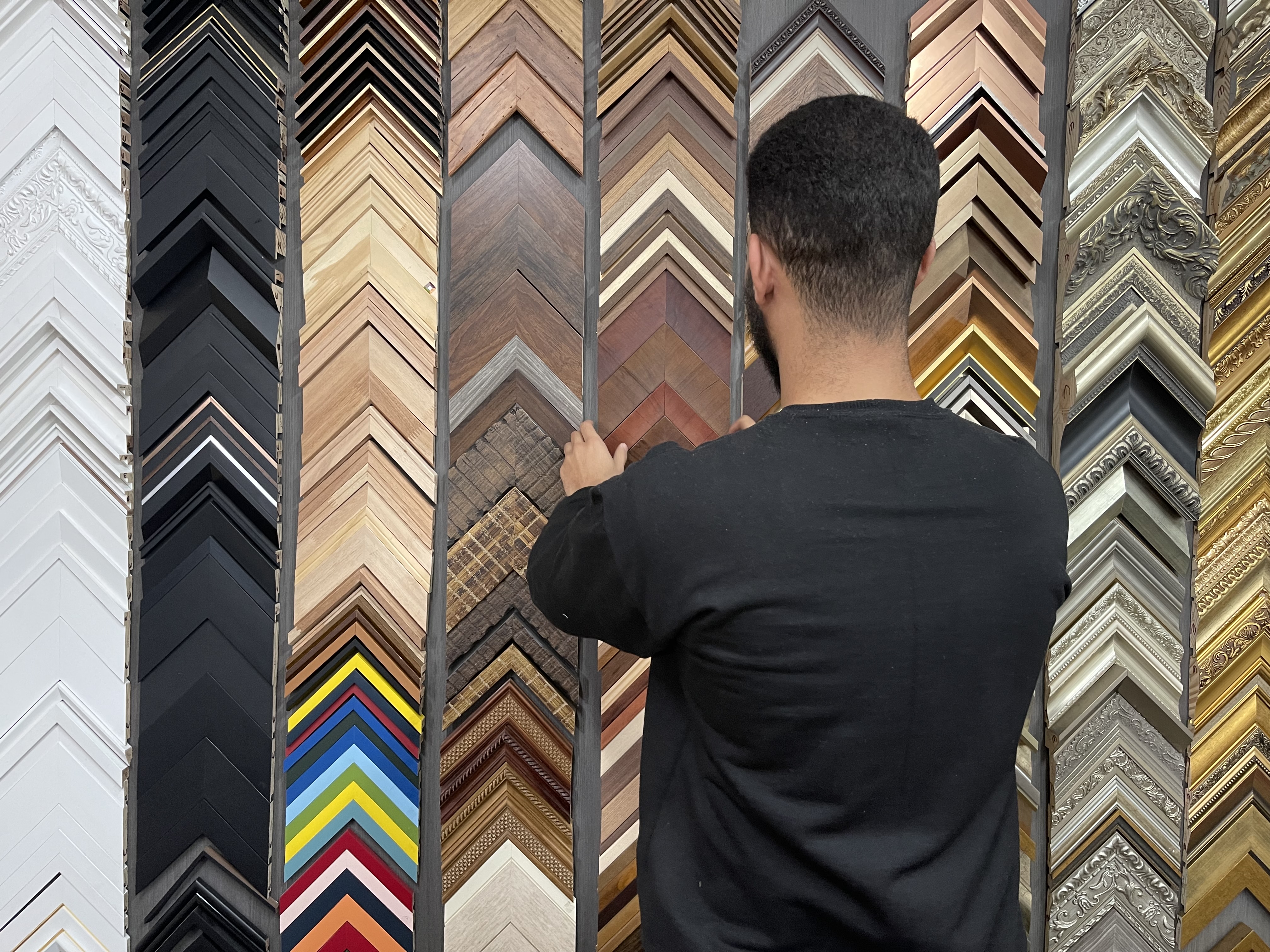 Fotografia de um vendedor tirando uma moldura do grande painel da FastFrame.