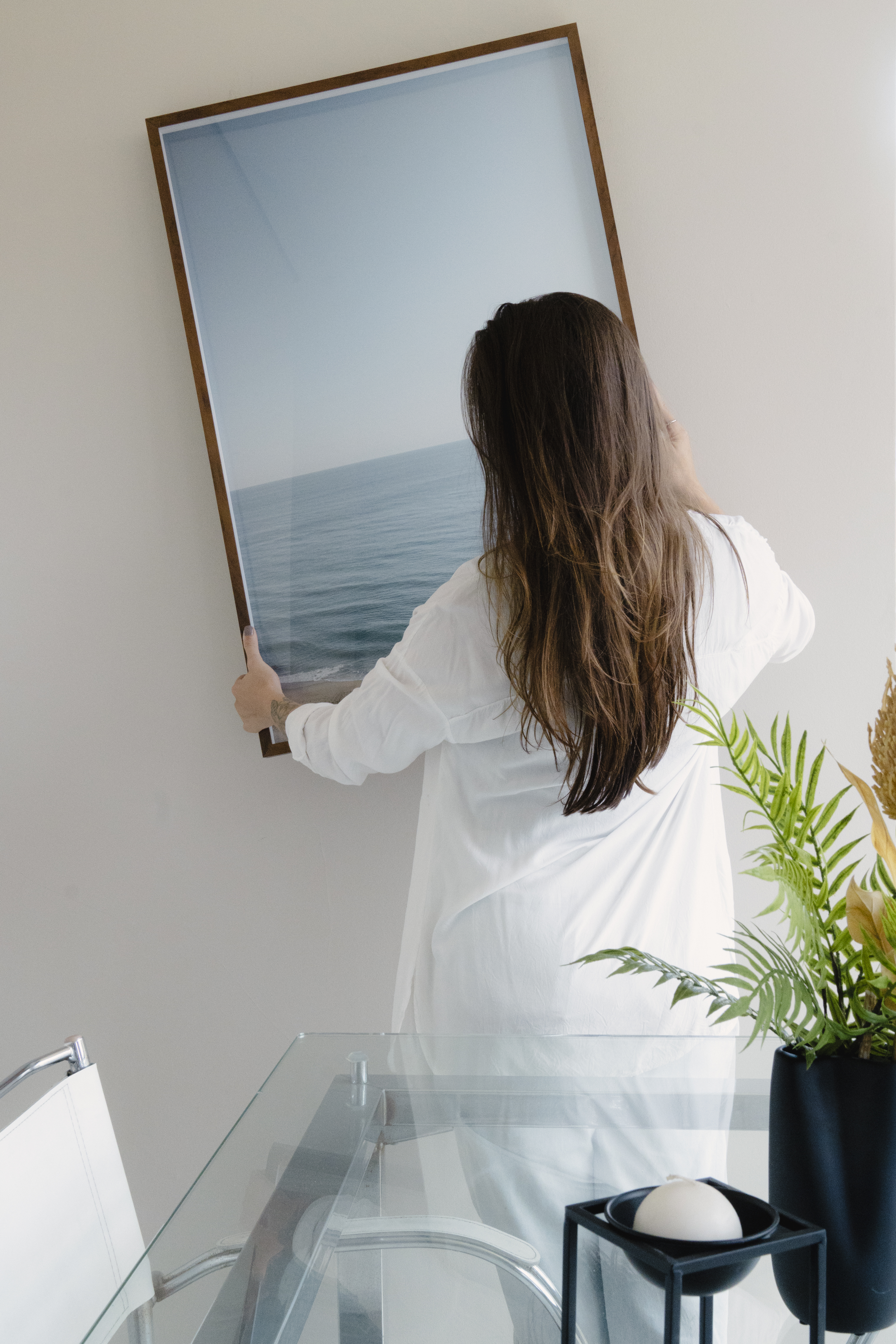 Fotografia da modelo colocando um quadro da marca FastFrame em um ambiente.